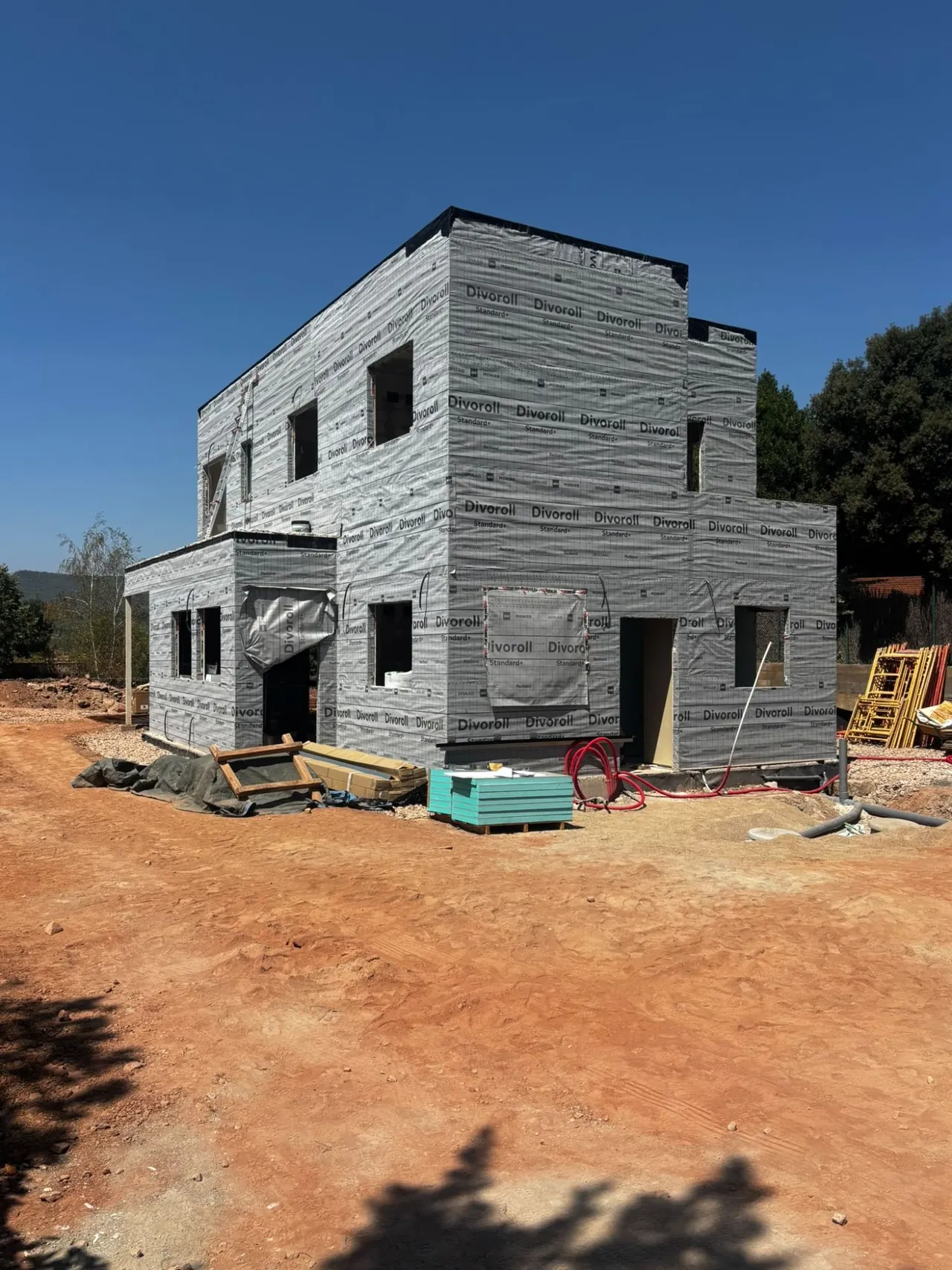 Vivienda de dos plantas en obra, con la fachada cubierta por la lámina de protección antes del revestimiento.